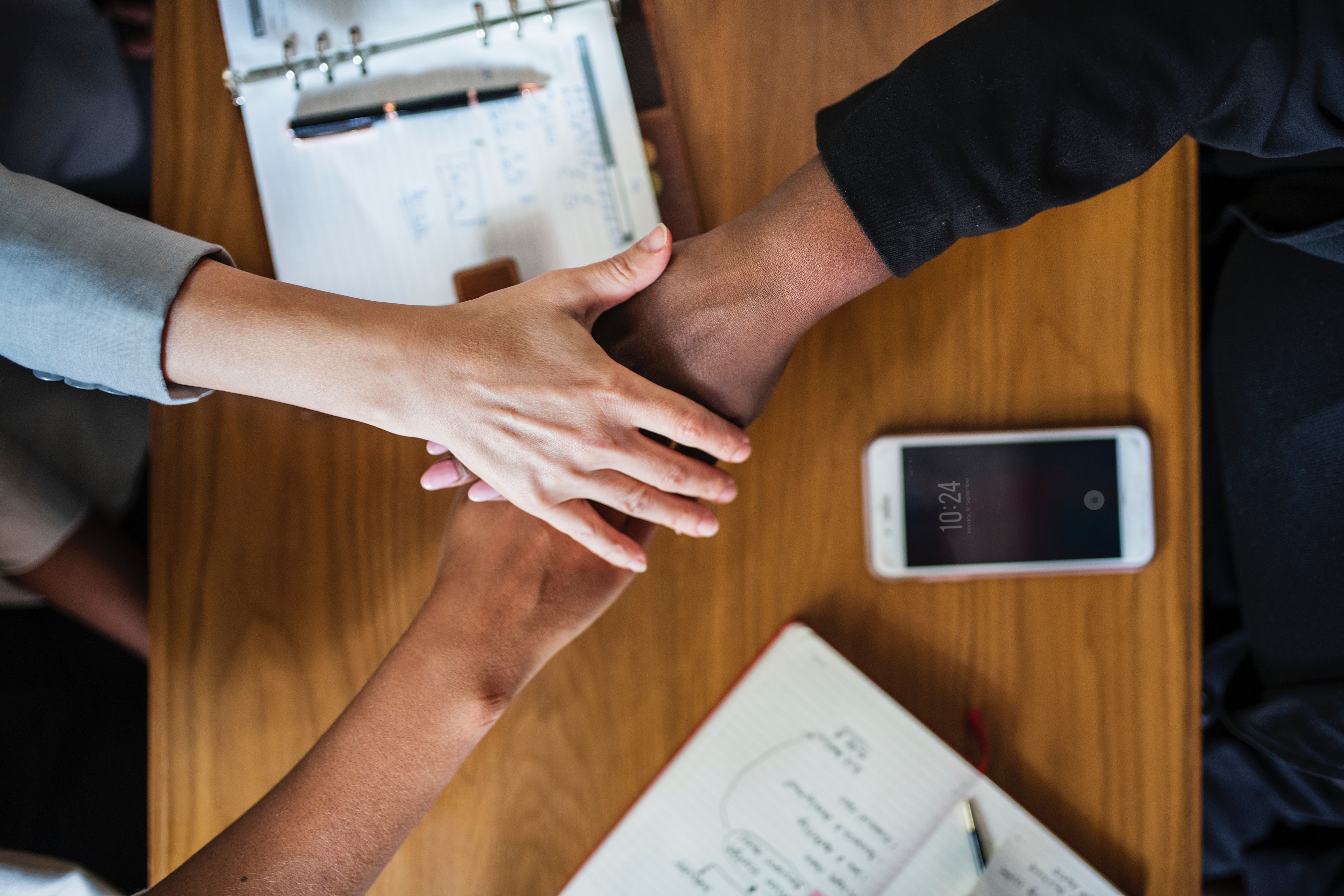 collaboration-cooperation-diversity-1430371.jpg Three people crossing hands above diary and smartphone